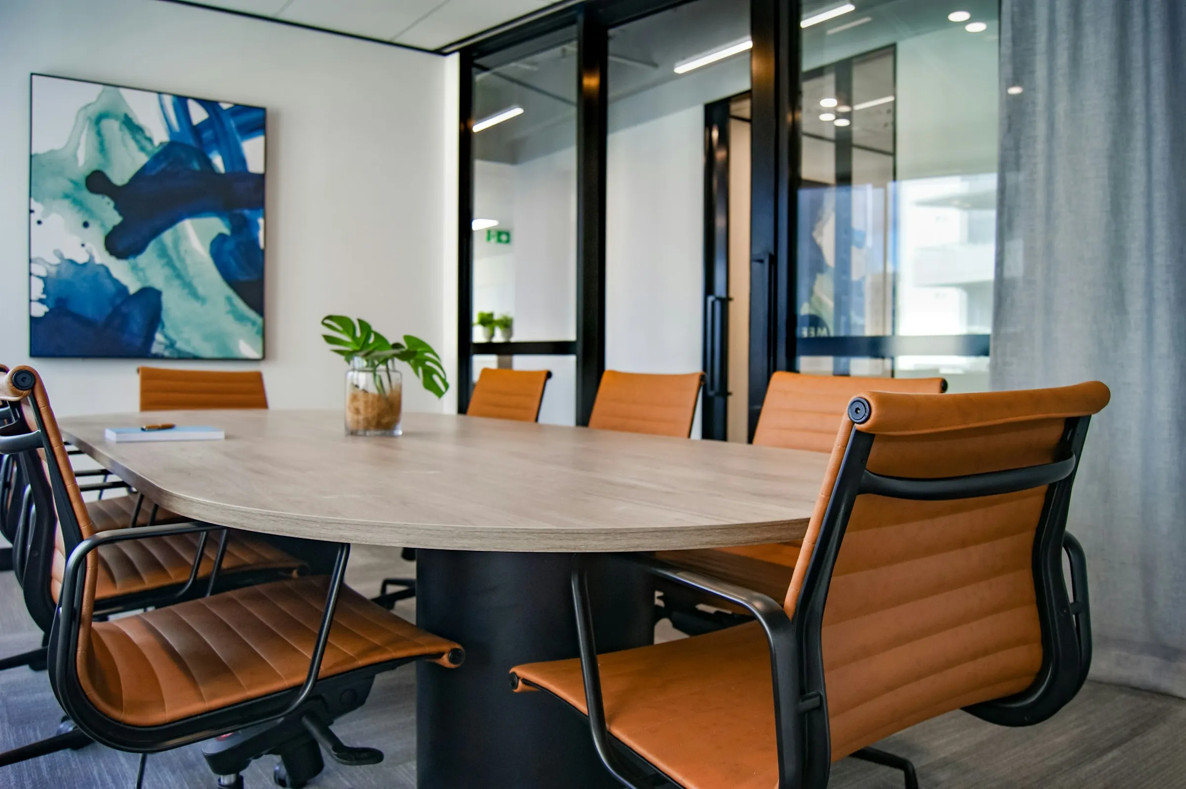 An empty boardroom with an oval wooden table and leather chairs